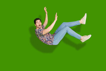 Canvas Print - Full size photo of speechless astonished guy dressed print shirt jeans falling down to empty space isolated on green color background