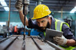 © eakgrungenerd - Man technician worker using tablet control setting up operating electric drill machinery of lathe metal factory industrial. Male worker wear yellow hardhat controlling iron drilling machine.