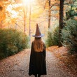 © Melvin - Back view of young girl with long hair wearing Halloween witch costume in autumn forest