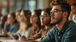 © Cambo27 - Young adults attending a college lecture, taking notes and listening intently to the professor