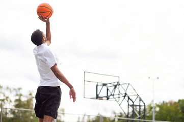 Male basketball player throwing the ball to the basket