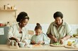 © Seventyfour - Medium shot of happy African American family of young smiling mother, daughter and grandmother chopping fresh vegetables while cooking healthy salad together on counter at beige kitchen, copy space