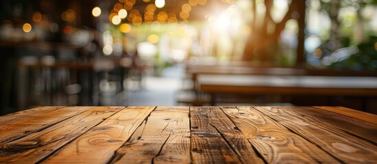 Poster - focused empty brown wooden table with a blurred coffee shop or restaurant background featuring bokeh