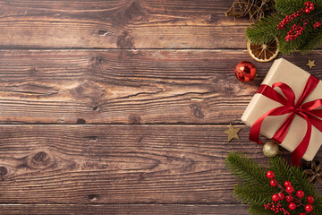 a beautifully wrapped christmas gift with a red ribbon sits on a wooden table alongside festive deco