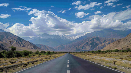 Wall Mural - A highway running parallel to a mountain range, with the road leading towards the distant peaks, under a sky filled with fluffy white clouds