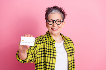 Poster - Photo of nice aged woman hold debit card checkered shirt isolated on pink color background