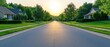 © AlgoCreative - A serene suburban street at sunrise, flanked by green lawns and charming houses, inviting tranquility and peaceful living. suburban development concept.