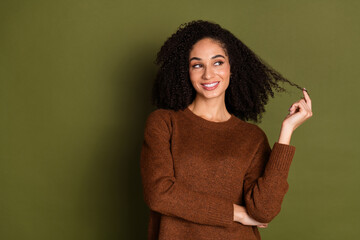 Poster - Portrait of pretty young woman hold hair look empty space wear sweater isolated on khaki color background