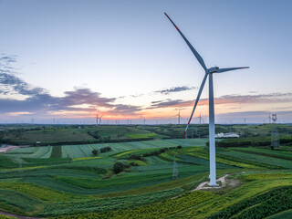 view of wind power turbine in field at sunset