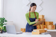© David - Startup SME small business entrepreneur SME or freelance Asian woman standing using a laptop with box, online marketing packaging box and delivery, SME concept.