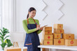 © David - Startup SME small business entrepreneur SME or freelance Asian woman standing using a laptop with box, online marketing packaging box and delivery, SME concept.