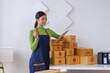 © David - Startup SME small business entrepreneur SME or freelance Asian woman standing using a laptop with box, online marketing packaging box and delivery, SME concept.