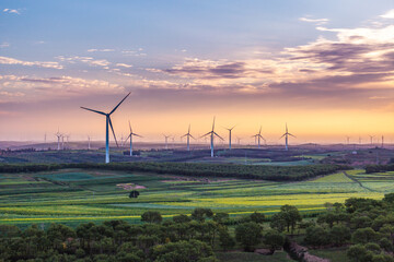 view of wind power turbine in field at sunset