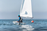 Sportsman steering dinghy sailing boat on calm sea