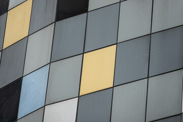 Wall Mural - A building with a lot of gray and yellow squares. The squares are of different sizes and are arranged in a way that creates a pattern. The building has a modern and industrial look to it