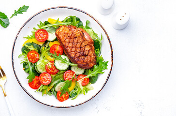 Tasty salad with grilled duck breast with vegetables and lettuce on white background, top view