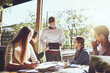© JordaanExams/peopleimages.com - Group, business people and presentation at cafe with tablet for discussion or remote work ideas on screen. Tech, team and meeting at restaurant for planning or learning with creative campaign manager