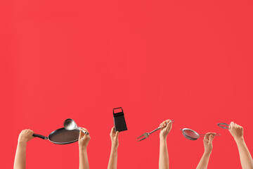 Female hands holding different kitchen utensils on red background