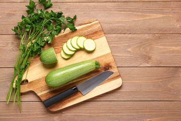 Board with slices of fresh zucchini and parsley on wooden background