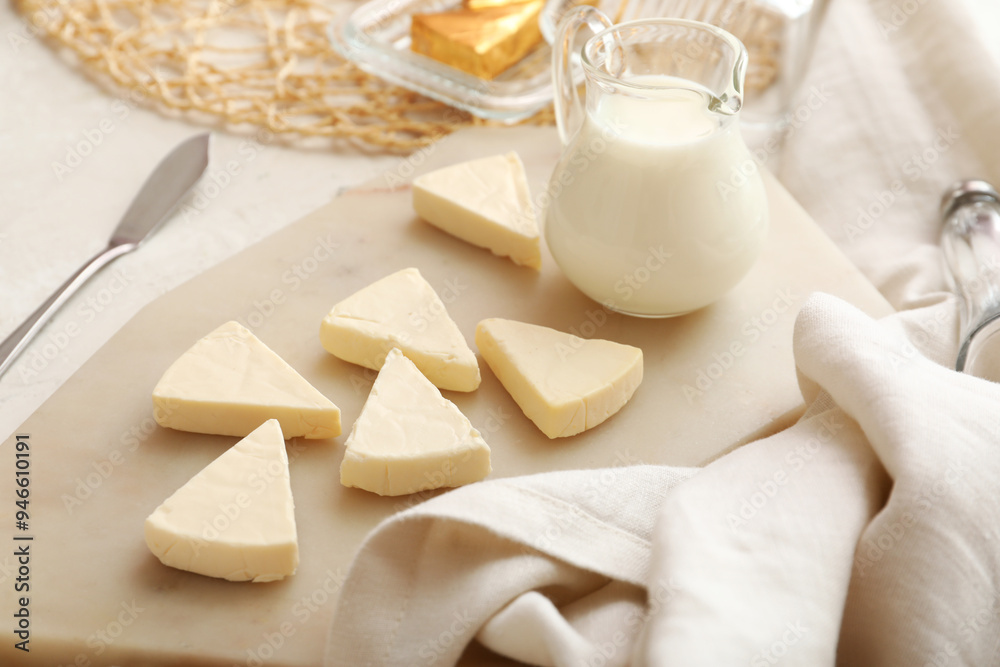 Board with triangles of tasty processed cheese and milk on light background, closeup