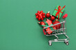 © Pixel-Shot - Small shopping cart with Christmas decor on green background