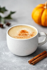 Sticker - Minimalist pumpkin spice latte in a sleek white cup with a tiny pumpkin and cinnamon stick beside it empty background with soft autumn tones 