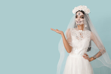 Sticker - Beautiful young woman dressed as dead bride for Halloween party pointing at something on blue background