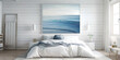 © Lila Patel - Soft, calming white walls and muted blue ocean paintings in a coastal bedroom.