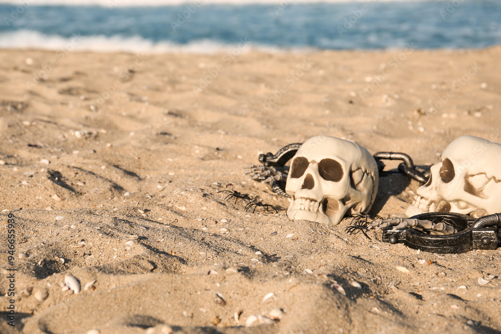 Skulls for Halloween with skeleton hands, spiders and chain on beach