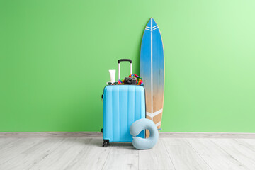 Sticker - Packed suitcase with neck pillow, surfboard and camera near green wall