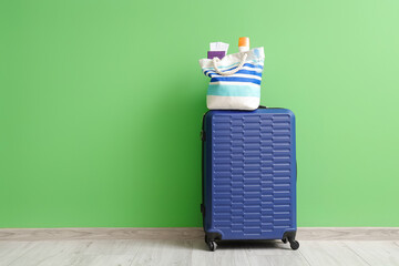 Wall Mural - Packed suitcase and beach bag with passports near green wall