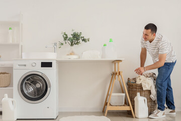 Canvas Print - Young man taking dirty clothes from basket in laundry room