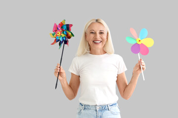 Wall Mural - Mature woman with toy windmills on light background