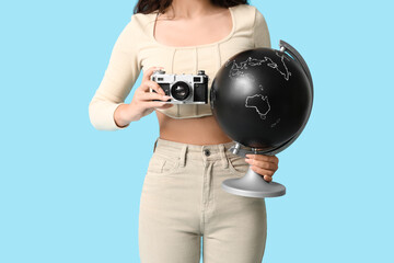 Wall Mural - Young Asian woman with globe taking photos on blue background. Travel concept