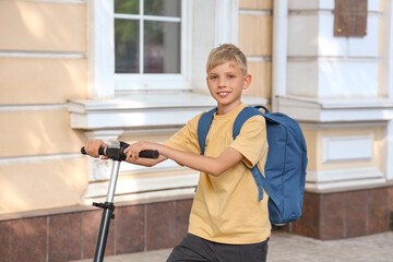 Poster - Cute schoolboy with modern electric kick scooter and backpack on city street