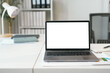 © amnaj - Modern laptop showing blank screen standing on desk with various stationery in bright office