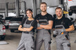 © anatoliycherkas - Group of three car service technician men and woman talking at workplace, people working together at vehicle repair garage service shop, check and repair customer car at automobile service center.