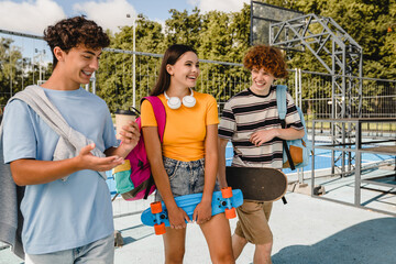 Wall Mural - Group of teenagers high school pupils classmates college students friends boys and girls with skateboards bags talking walking laughing out hanging out having fun in skate park sport court outside