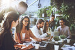 © JordaanExams/peopleimages.com - Team, meeting or laptop at table for small business, budget planning or marketing strategy in coffee shop. Startup, group or stats on documents for brainstorming, company finance growth or discussion