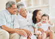 © peopleimages.com - Love, sofa and grandparents with baby and child in home for bonding, connection or family. Smile, happy and senior man and woman holding infant with girl kid sibling in living room at house.