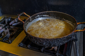 Old pan frying food in boiling oil on a stove