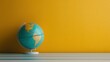 ©  lukaPixMedia - A detailed globe depicting the Americas, resting on a blue-striped surface against a vibrant yellow background, symbolizing global studies and adventure.