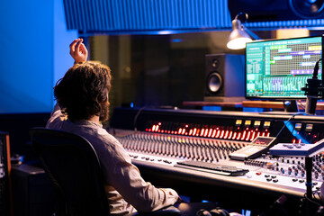 Leinwandbilder - Sound designer counting down for singer in vocal booth to start performance for recording session, producing new music in control room. Skilled audio engineer operating panel board.