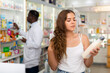 © JackF - Young woman with brown hair electing haircare shampoo in drugstore