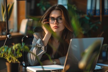 Poster - A woman sits in front of a laptop computer, focused on her work
