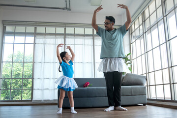 Father wears a ballet tutu and dances according to the moves his daughter performs at home