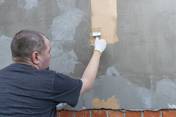 Wall Mural - A man is painting a wall with a brush