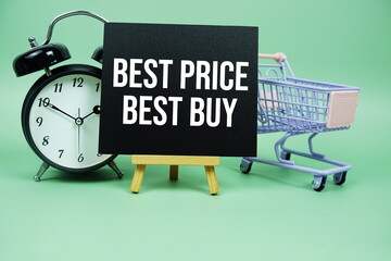 Wall Mural - Best Price Best Buy text message on paper card with alarm clcok and trolley shopping cart on green background