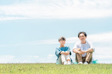 Canvas Print - 青空の見える公園・丘に座る家族・親子（父親・娘・シングルファーザー）
