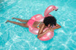 © VISTA by Westend61 - Young woman floating on water with inflatable float in pool